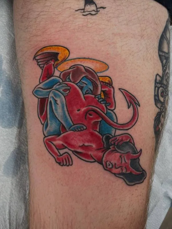 American Traditional color tattoo of a blue angel cherub with halo wrestling a red devil cherub with horns and tail on the forearm, by Franky Sharpz at Wailana Tattoo, Waikiki, Hawaii.