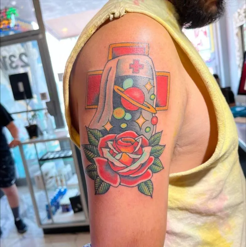 American Traditional color tattoo of a nurse helmet, Saturn and bubbles floating above a red cross with a Traditional rose at the base, on the upper arm, by Franky Sharpz at Wailana Tattoo, Waikiki, Hawaii.